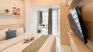 Un hotel moderno con una cama, un escritorio, un televisor y vistas de la ciudad a través de la ventana.