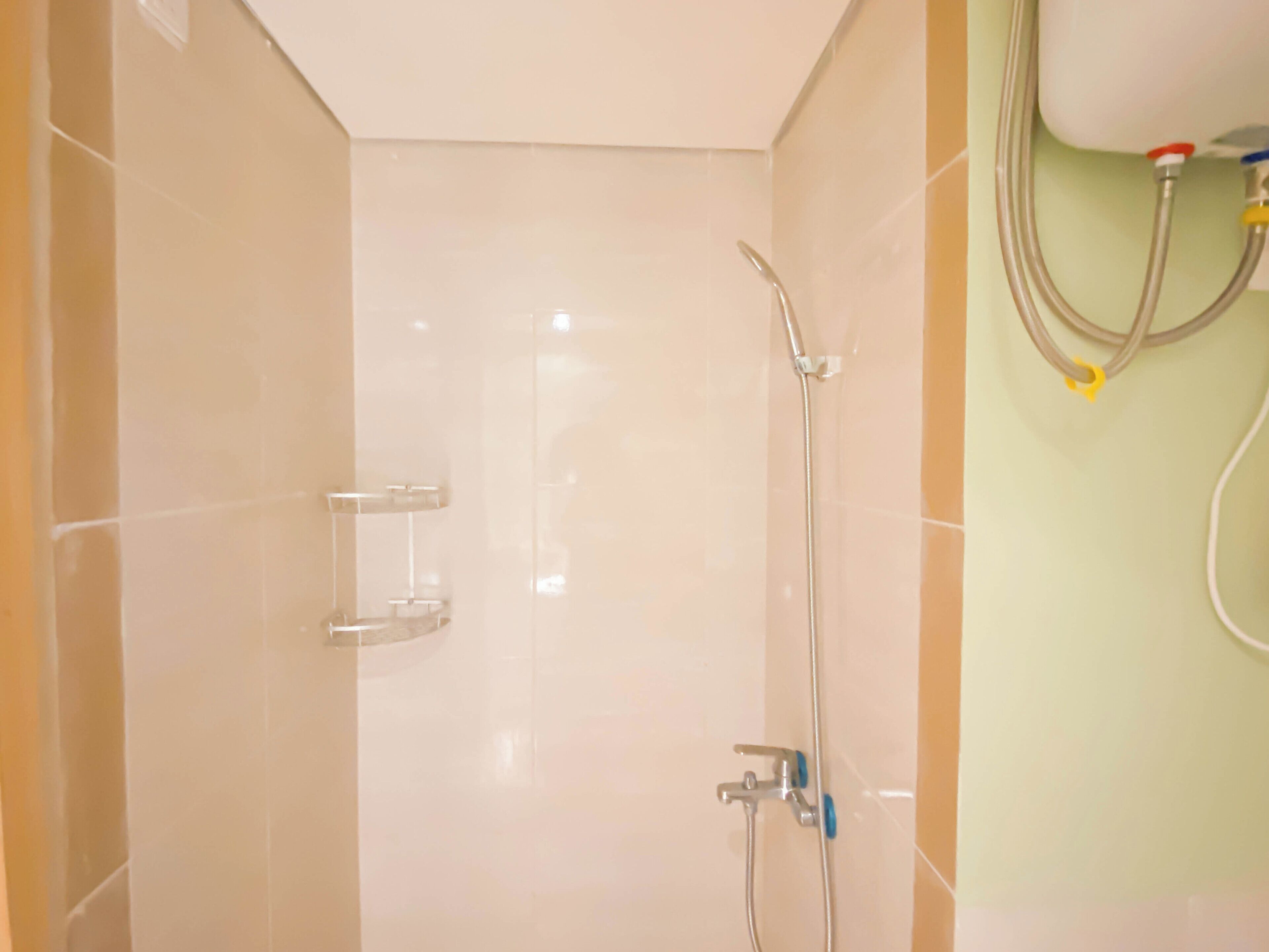 A bathroom with a shower, a towel rack, and a wall-mounted pipe.