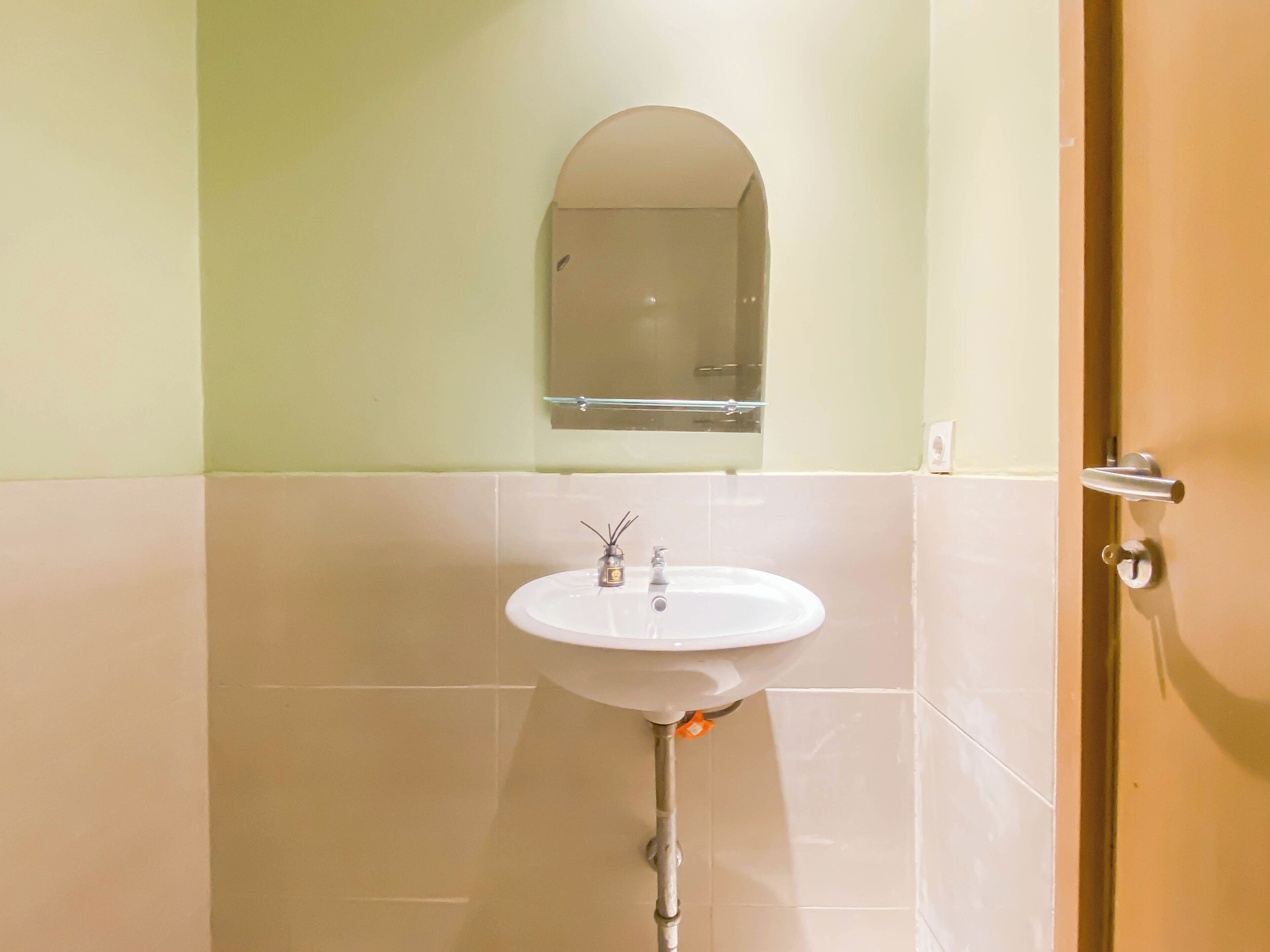 A bathroom with a white sink, a mirror above it, and a door to the right.