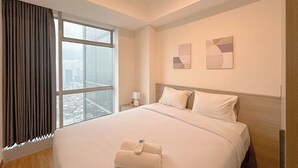 Une chambre d’hôtel avec un grand lit, une fenêtre avec des rideaux, une table de chevet avec une lampe et deux œuvres d’art murales.