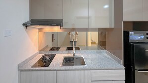 A modern kitchen with a granite countertop, stainless steel sink, and a built-in oven. - Modern Suite 1Br At Grand Sungkono Lagoon Apartment (Surabaya)