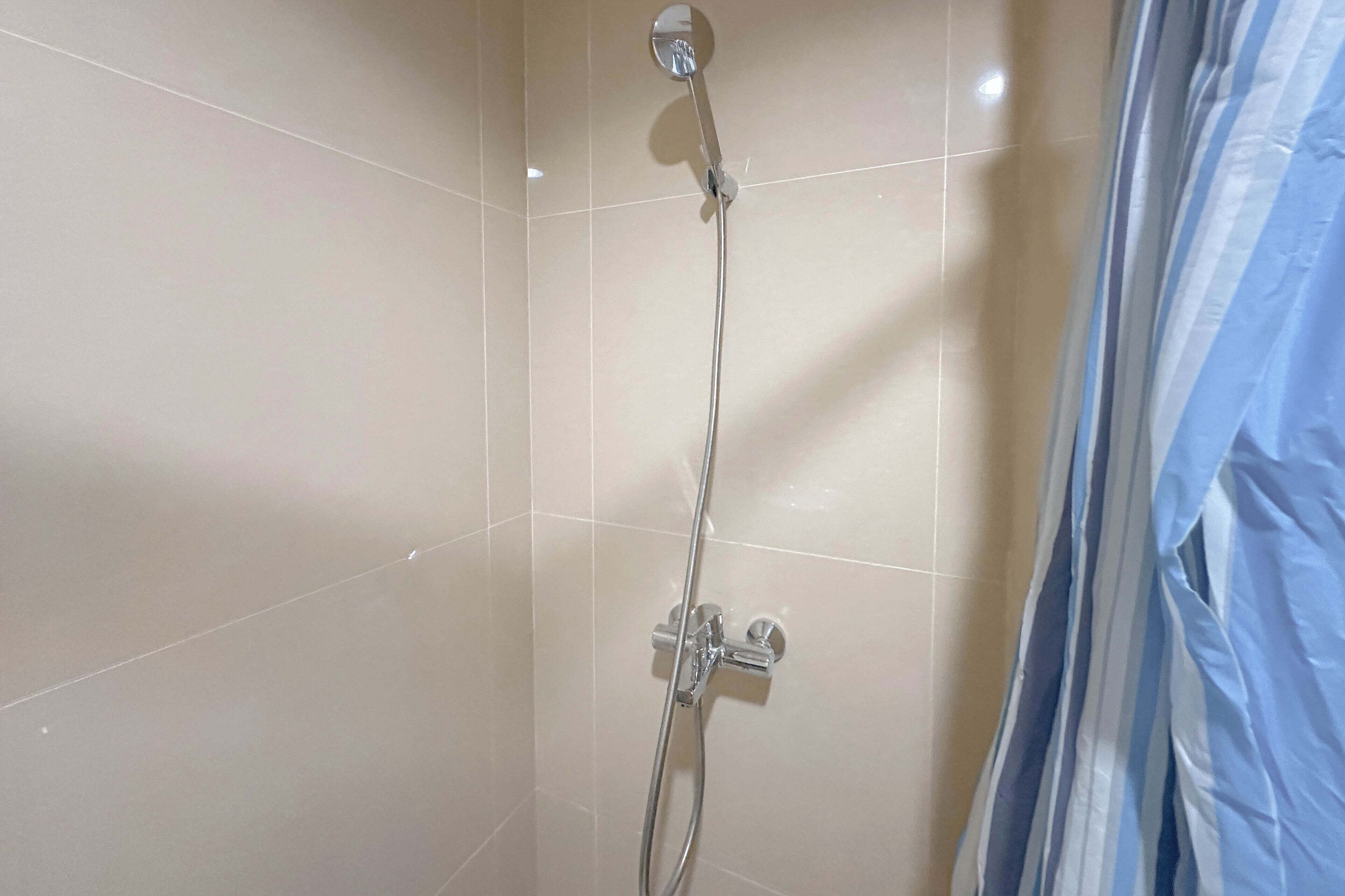 A shower with a handheld showerhead and a wall-mounted control valve.