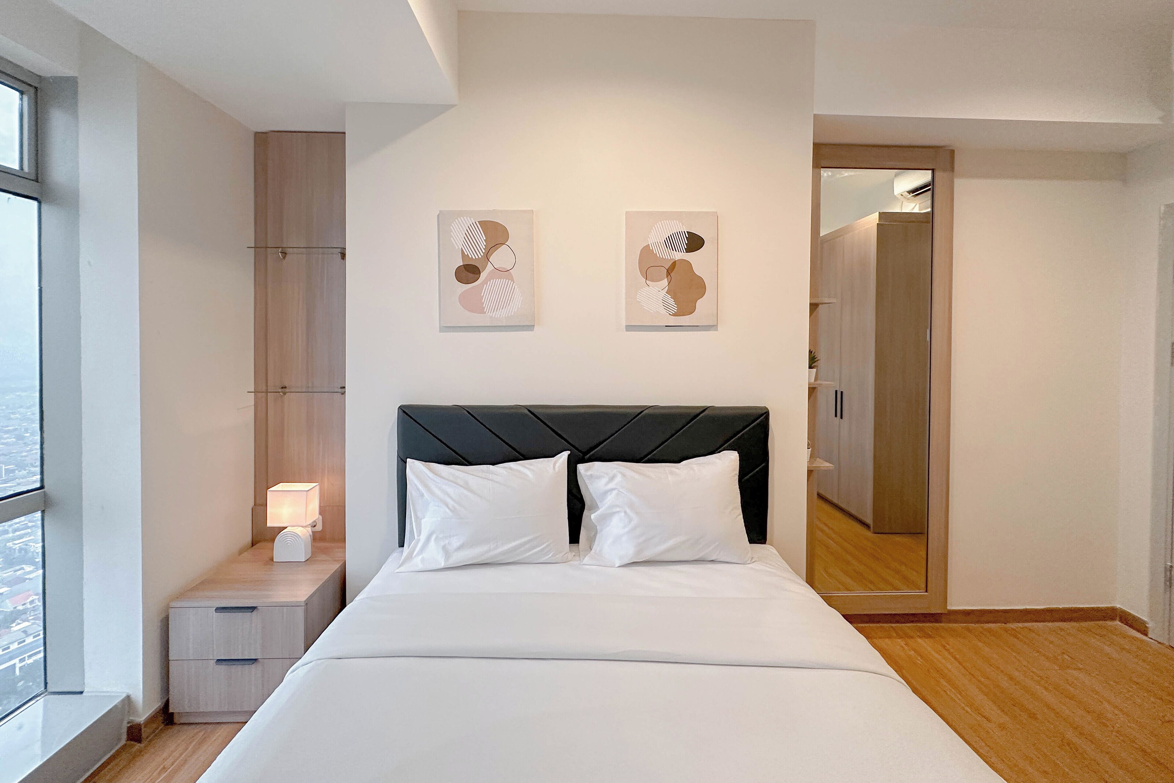 Een moderne hotelkamer met een groot bed, een nachtkastje met een lamp en twee decoratieve wandpanelen.