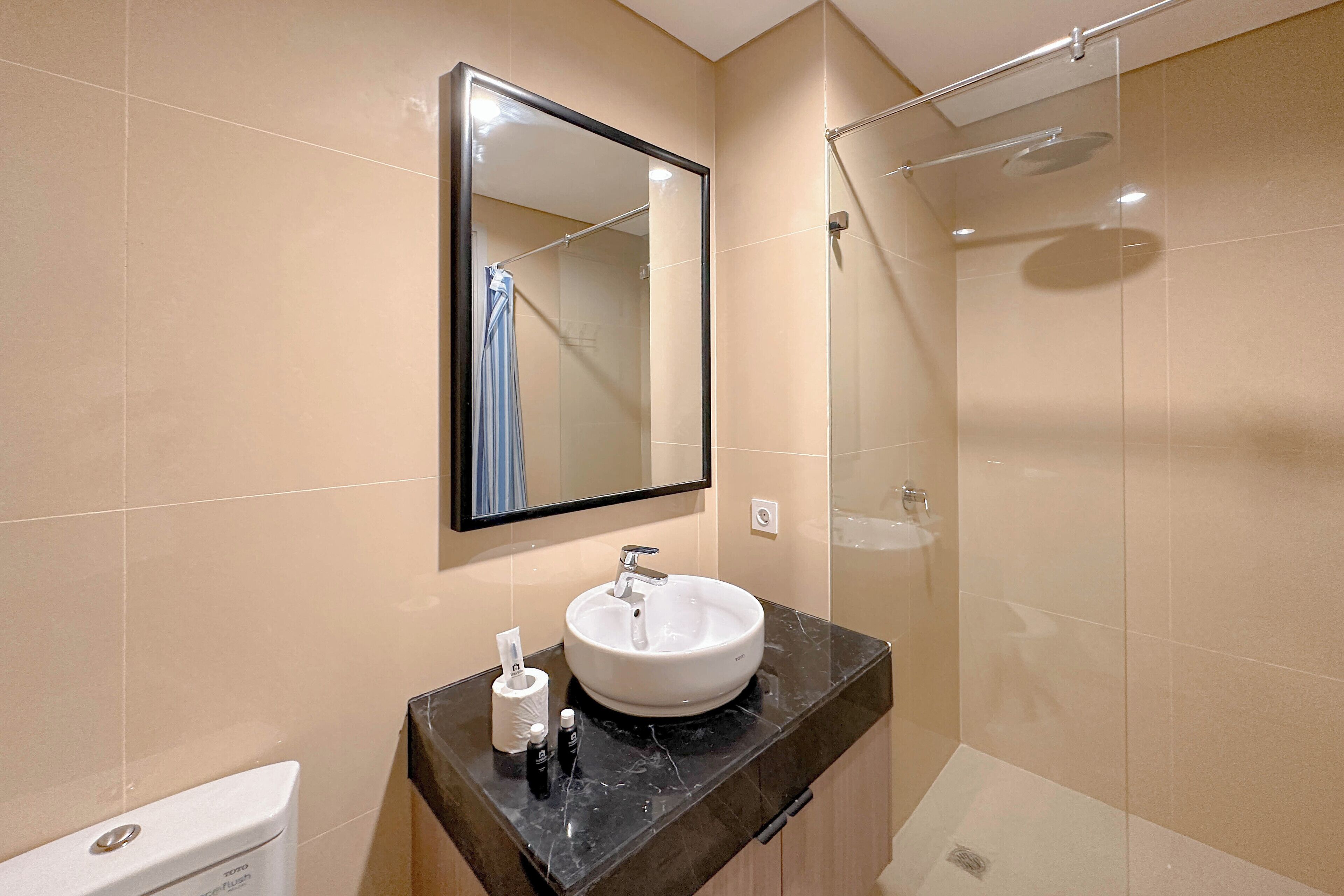 A bathroom with a white sink, a mirror, a toilet, and a shower.