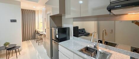 A modern kitchen with a built-in stove, a sink, and a dining area with a table and chairs.