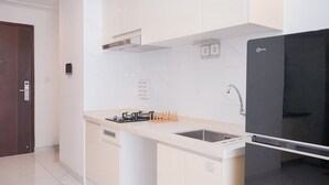 Une cuisine moderne avec des meubles blancs, un réfrigérateur noir et un évier en acier inoxydable.