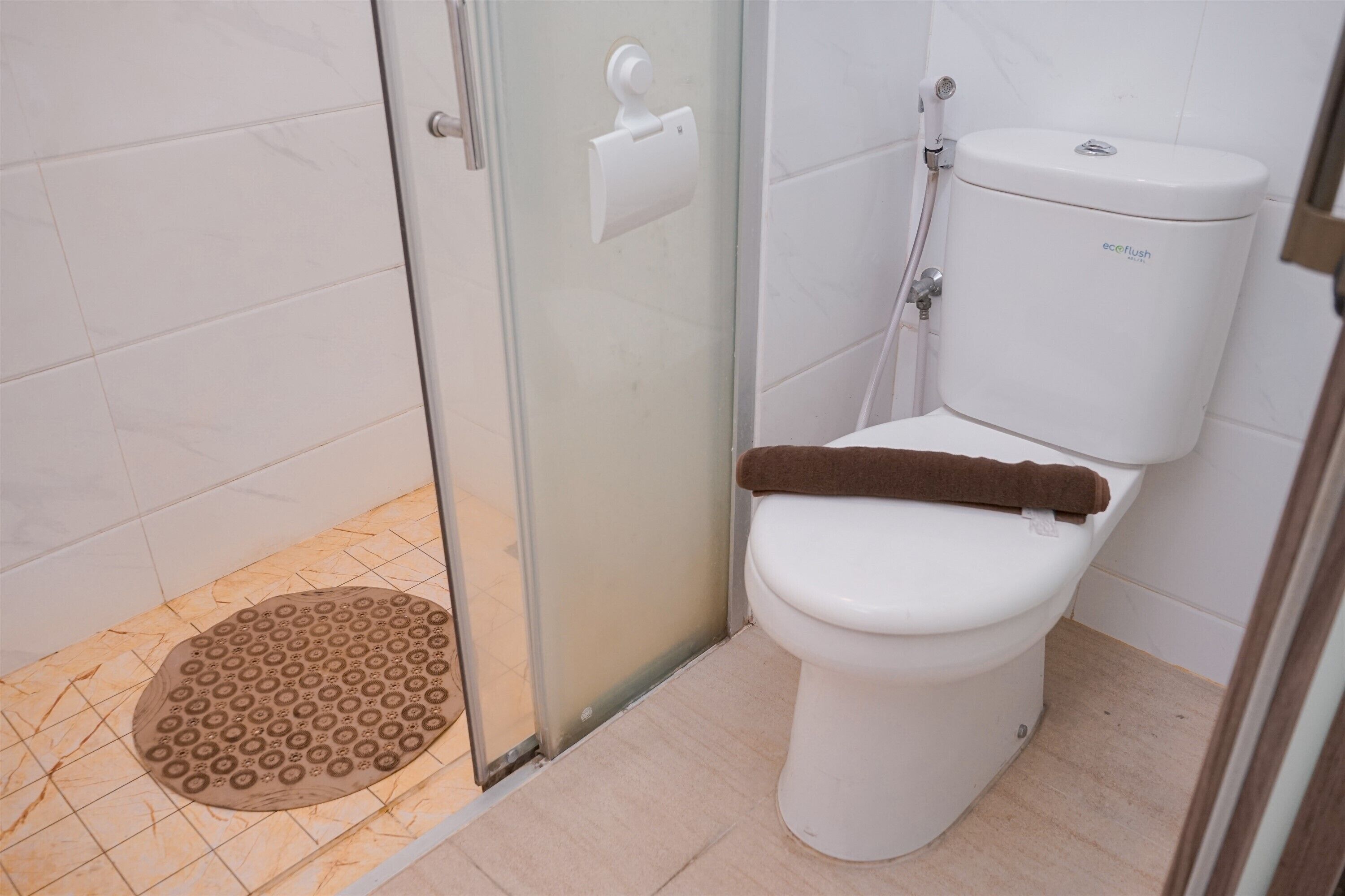 A bathroom with a toilet, a shower, and a glass door.