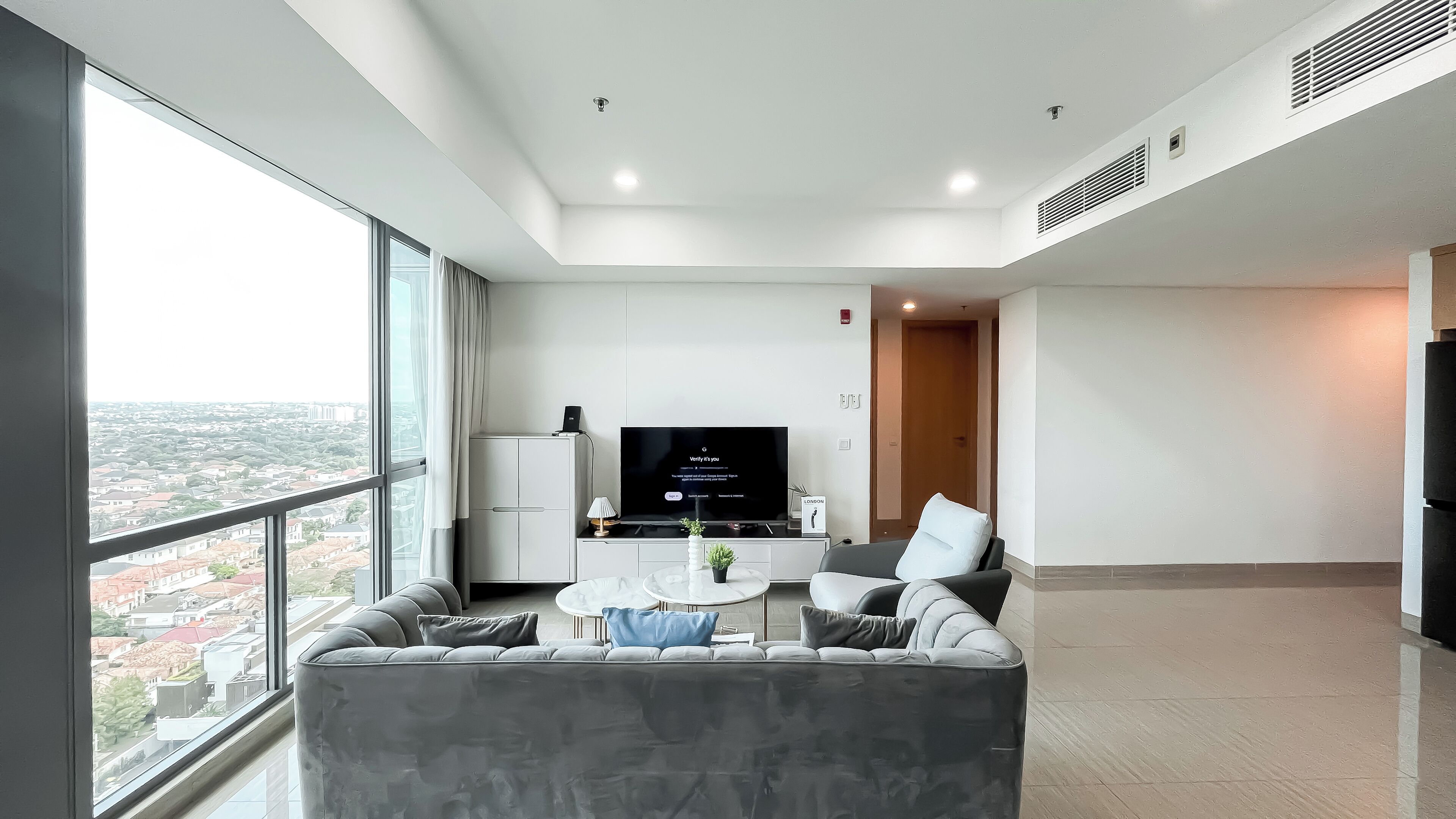 A modern living room with a large window, a flat-screen TV, a sofa, and a coffee table.
