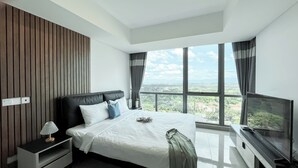 Una habitación de hotel moderna con una cama grande, televisión y vistas a un paisaje urbano a través de amplios ventanales.