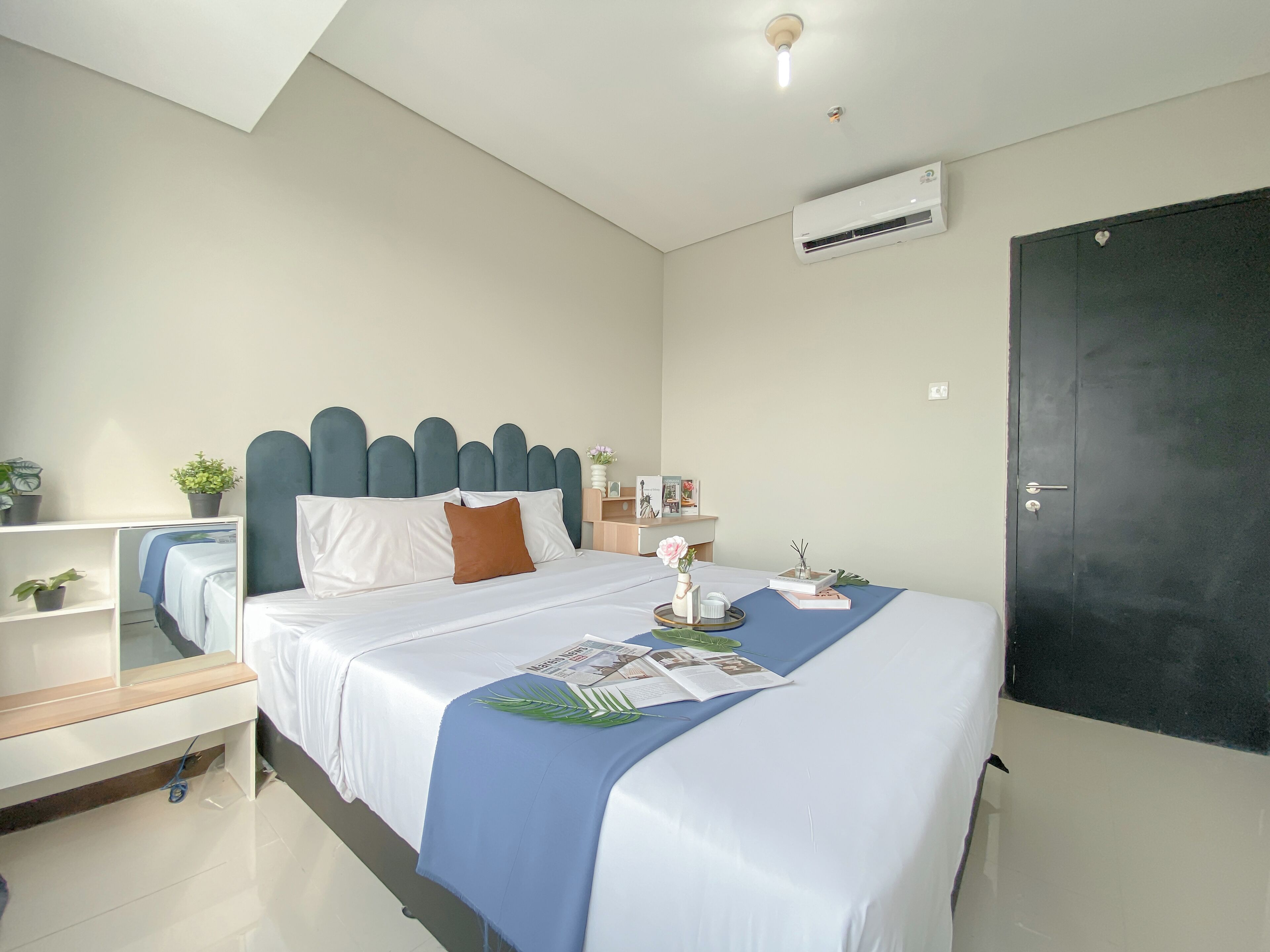 Een keurig opgemaakt slaapkamer met een bed, nachtkastjes, een kledingkast en een airconditioning.