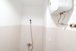 A shower with a handheld showerhead and a wall-mounted control panel.