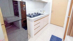 Een kleine keuken met een koelkast, fornuis en witte kasten.