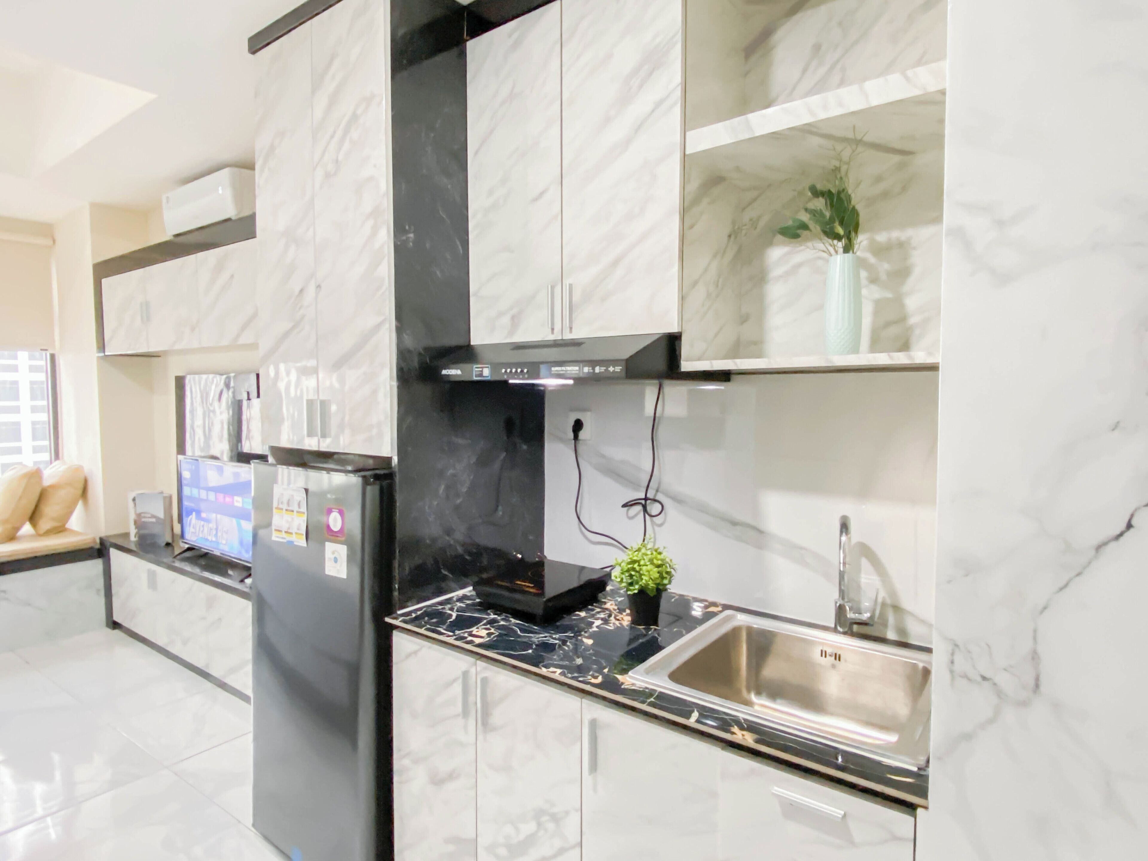 A modern kitchen with marble countertops, a stainless steel sink, and a black range hood.