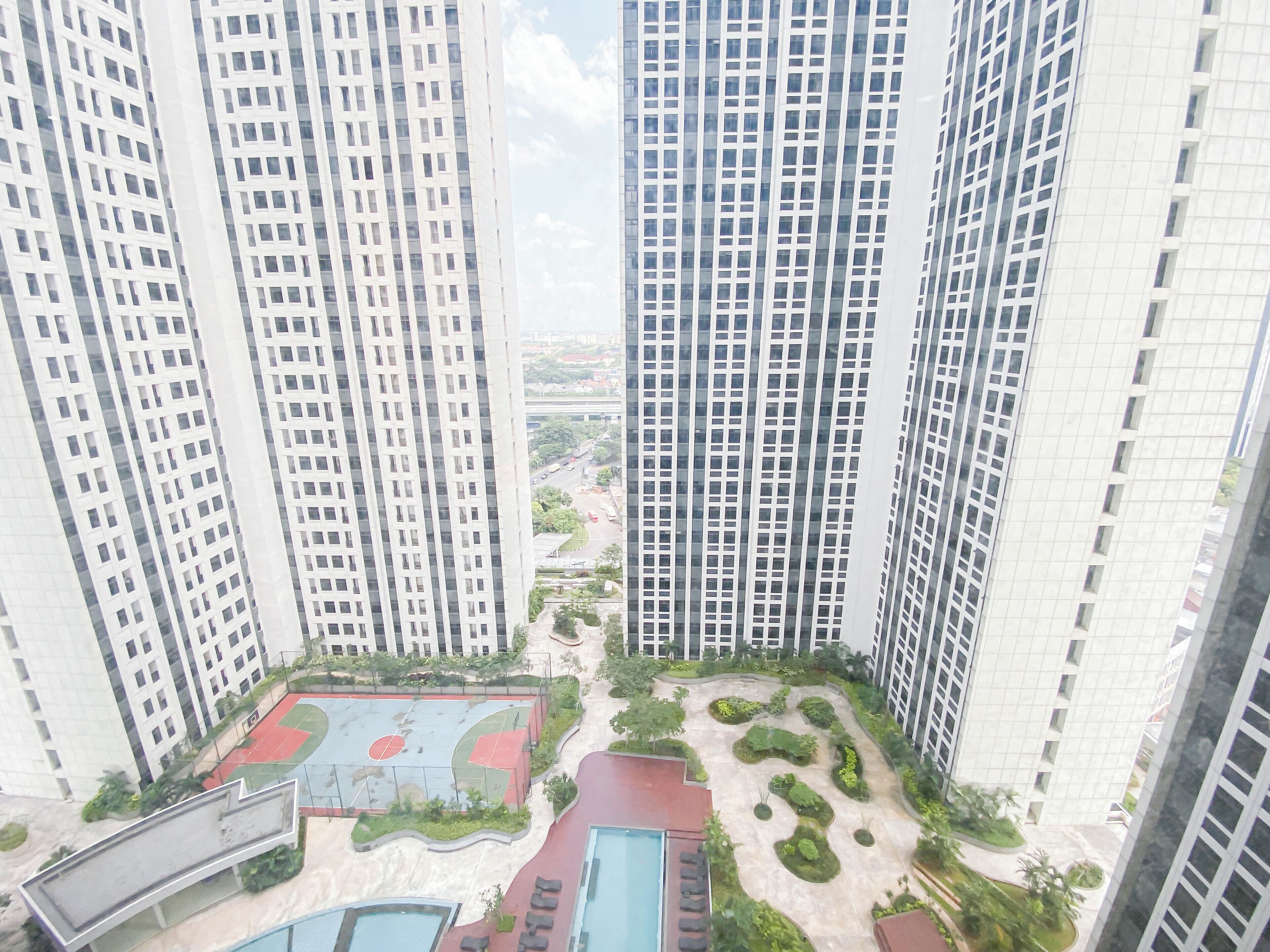 A high-rise building with multiple floors, a basketball court, and landscaped areas.