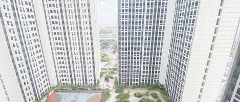 A high-rise building with multiple floors, a basketball court, and landscaped areas.