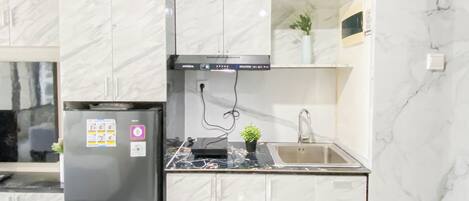 A modern kitchen with marble countertops, a built-in oven, and a stainless steel sink.