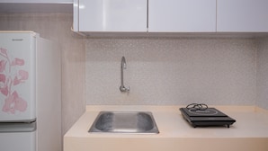 A kitchen with a white refrigerator, a sink, and a black device on the countertop.