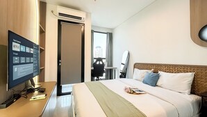 Une chambre d’hôtel avec un lit, un téléviseur affichant un menu, un appareil de climatisation et une vue sur les bâtiments à l’extérieur de la fenêtre.