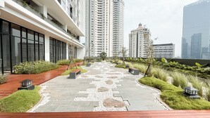Un chemin urbain moderne, composé d’un mélange de pierre et d’herbe, bordé d’immeubles de grande hauteur et de verdure.