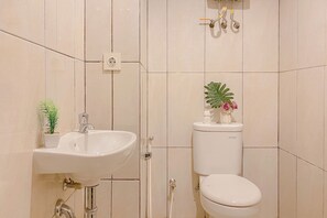 Une salle de bain avec un lavabo blanc, des toilettes et une plante en pot.