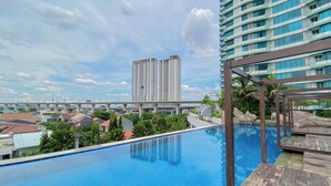 A swimming pool with a view of high-rise buildings and a bridge in the background. - Good Choice And Homey Studio Grand Kamala Lagoon Apartment (Bekasi)