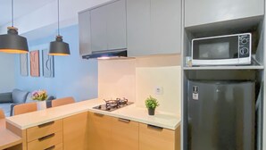 Una cocina moderna con armarios grises, un refrigerador negro, un microondas y luces colgantes.