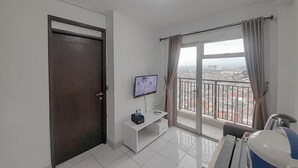 Una sala de estar moderna con televisor, un mueble blanco y un balcón con vistas a la ciudad.