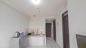 Un pasillo estrecho con una zona de kitchenette que incluye un lavamanos, un refrigerador pequeño y una encimera con una tetera y otros utensilios de cocina.