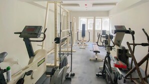 Une salle de sport équipée de divers appareils d’exercice, notamment des tapis de course, des vélos d’appartement et des appareils de musculation.