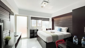 Une chambre d’hôtel moderne équipée d’un lit, de tables de chevet, d’un bureau et d’une chaise.