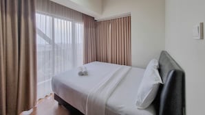 Una habitación de hotel con una cama, cortinas y un ventanal.
