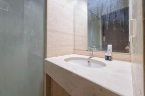 A bathroom with a white sink, a mirror, and a glass shower enclosure.