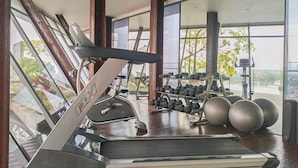 Un gimnasio con cinta de correr, mancuernas y pelotas de ejercicio.