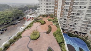 Un edificio residencial alto con azotea ajardinada que cuenta con senderos serpenteantes y jardineras verdes.