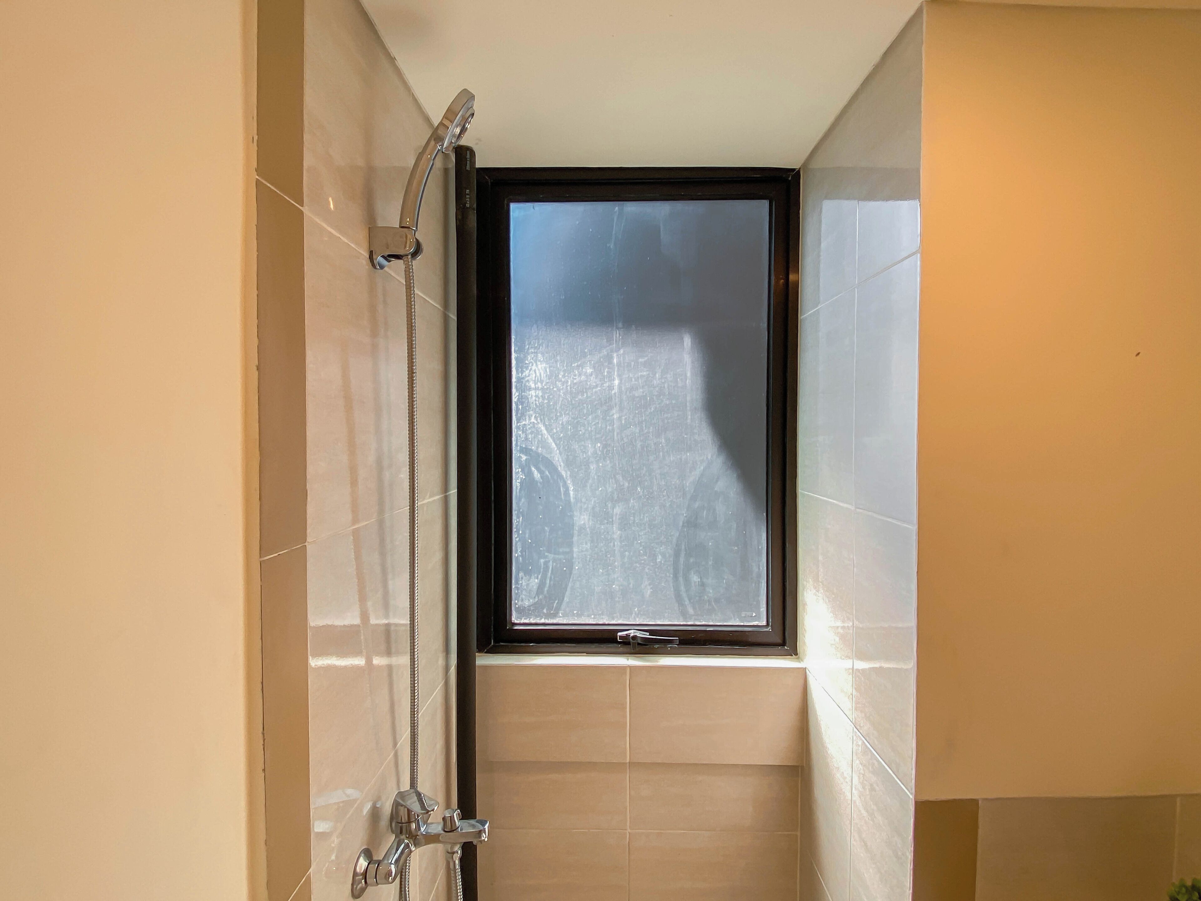 Une salle de bain avec une douche, une fenêtre et des murs carrelés.