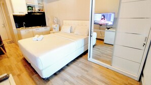 Una habitación de hotel con cama, televisión, kitchenette y armario.