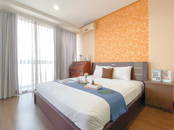 A hotel room with a large bed, a nightstand, a dresser, and a window with curtains. - Nice And Homey Studio Apartment At Kemang Mansion (Jakarta)