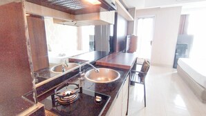 A modern kitchen with a stainless steel sink, a gas stove, and a built-in oven. - Comfy And Classic Studio At Grand Sungkono Lagoon Apartment (Surabaya)