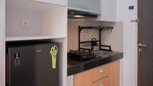 A compact kitchen with a refrigerator, a microwave, and a sink. - Warm And Cozy Studio Apartment At Serpong Garden (Cisauk)