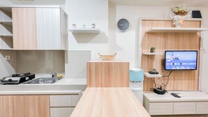 Una cocina moderna con encimera de madera, un fregadero, una cafetera y un televisor montado en la pared.