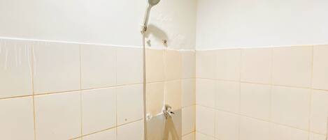 Eine Dusche mit Duschbrause und Wandarmatur in einem gefliesten Badezimmer.