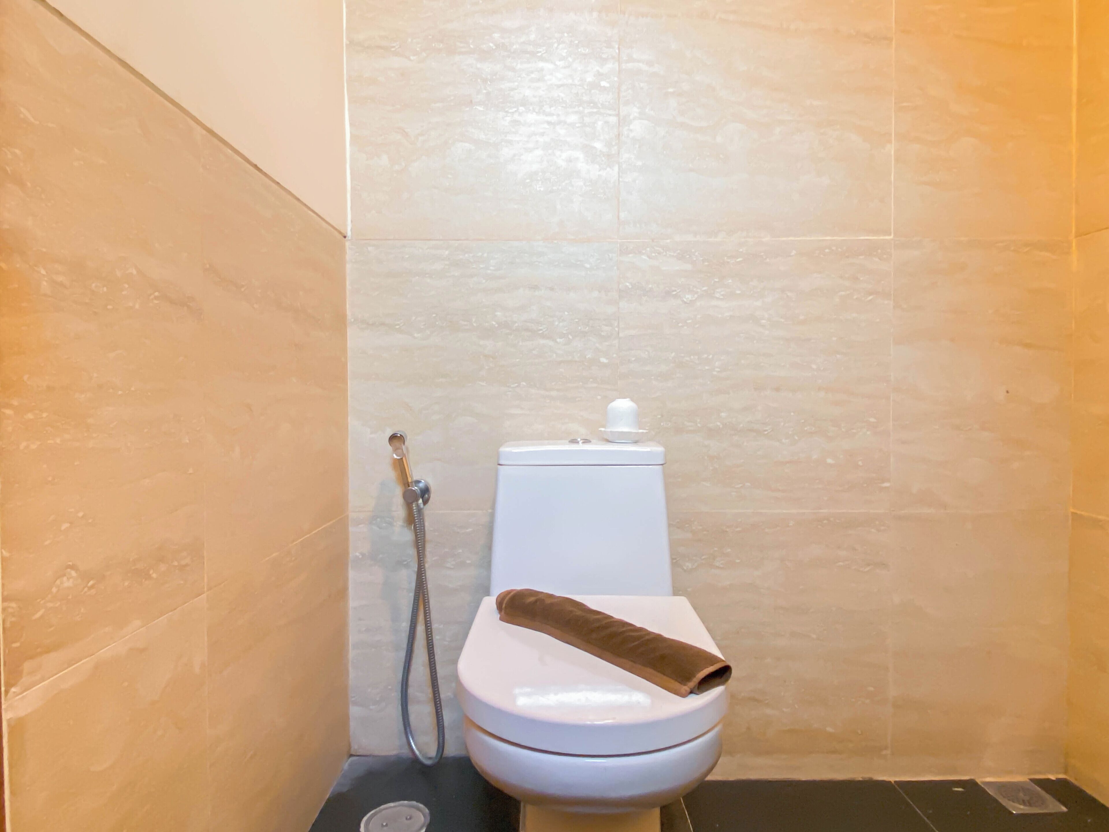 A bathroom with a toilet, a shower, and a towel on the toilet seat.
