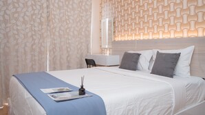 A neatly made bed with a blue bedspread, white pillows, and a bedside table with a lamp. - Good And Comfy 1Br Apartment At M-Town Signature (Gading Serpong)