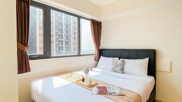 A neatly made bed with a magazine, a tray with a vase, and a pillow. - Best Choice And Comfy 2Br At Apartment Meikarta (Cikarang)