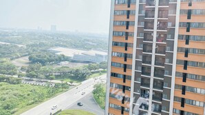 A high-rise building with multiple balconies, a clear view of the surrounding greenery, and a road with vehicles. - Best Choice And Comfy 2Br At Apartment Meikarta (Cikarang)