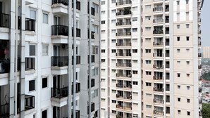 A high-rise residential building with multiple balconies, large windows, and a uniform architectural style.