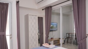 A modern bedroom with a bed, a desk, and a TV. - Elegant And Homey 1Br Apartment Tamansari Bintaro Mansion (South Tangerang)