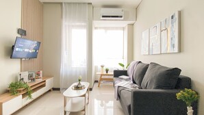A modern living room with a grey sofa, a small white table, and a TV mounted on the wall.