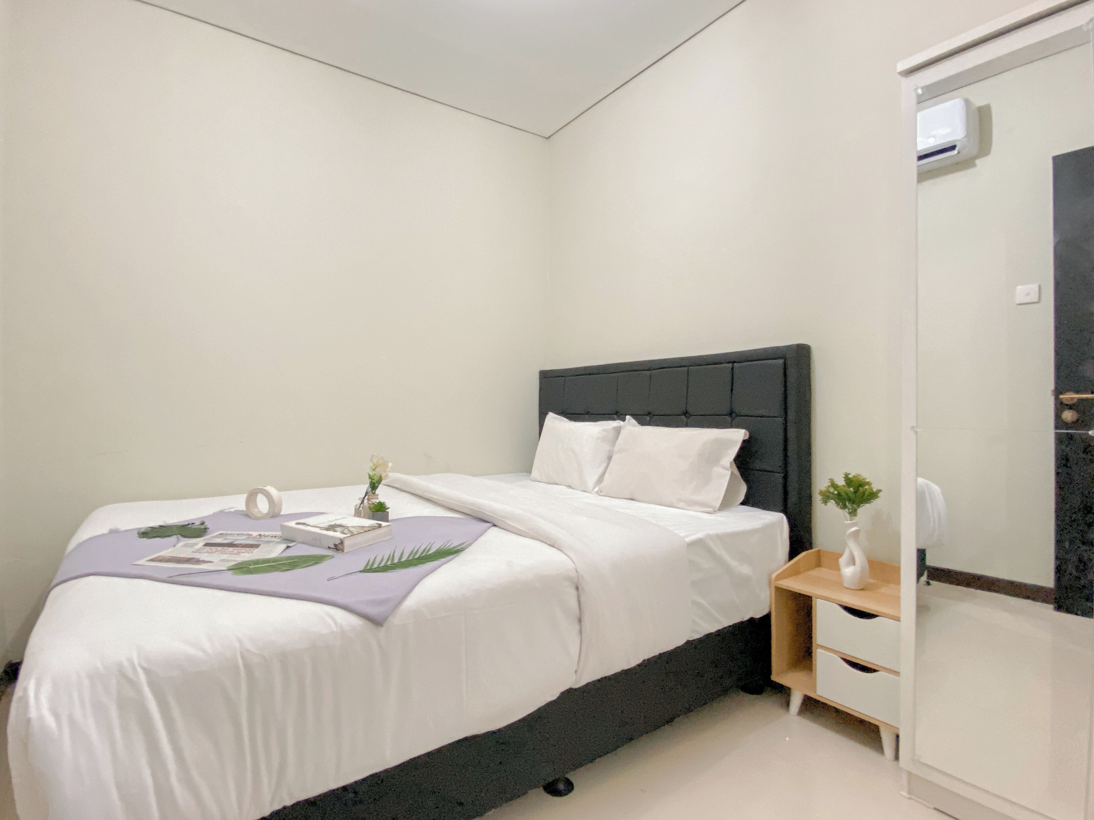 A bedroom with a bed, bedside table, and a mirror.