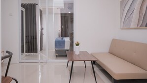 Uma sala de estar moderna com um sofá, uma mesinha e uma porta de vidro deslizante para uma varanda.